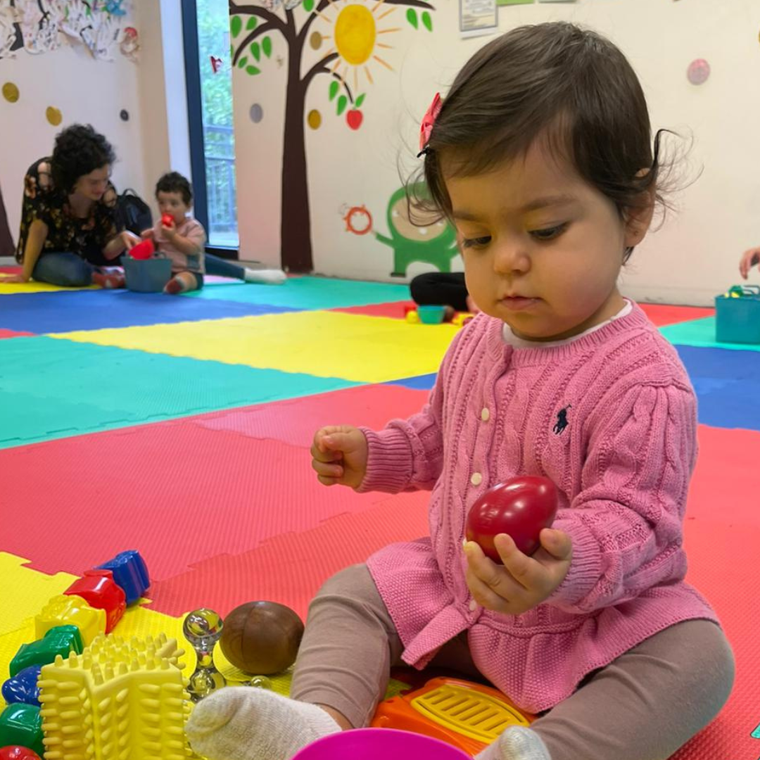 Infant shaking an egg shaker during a music play session at Busy Bees Music