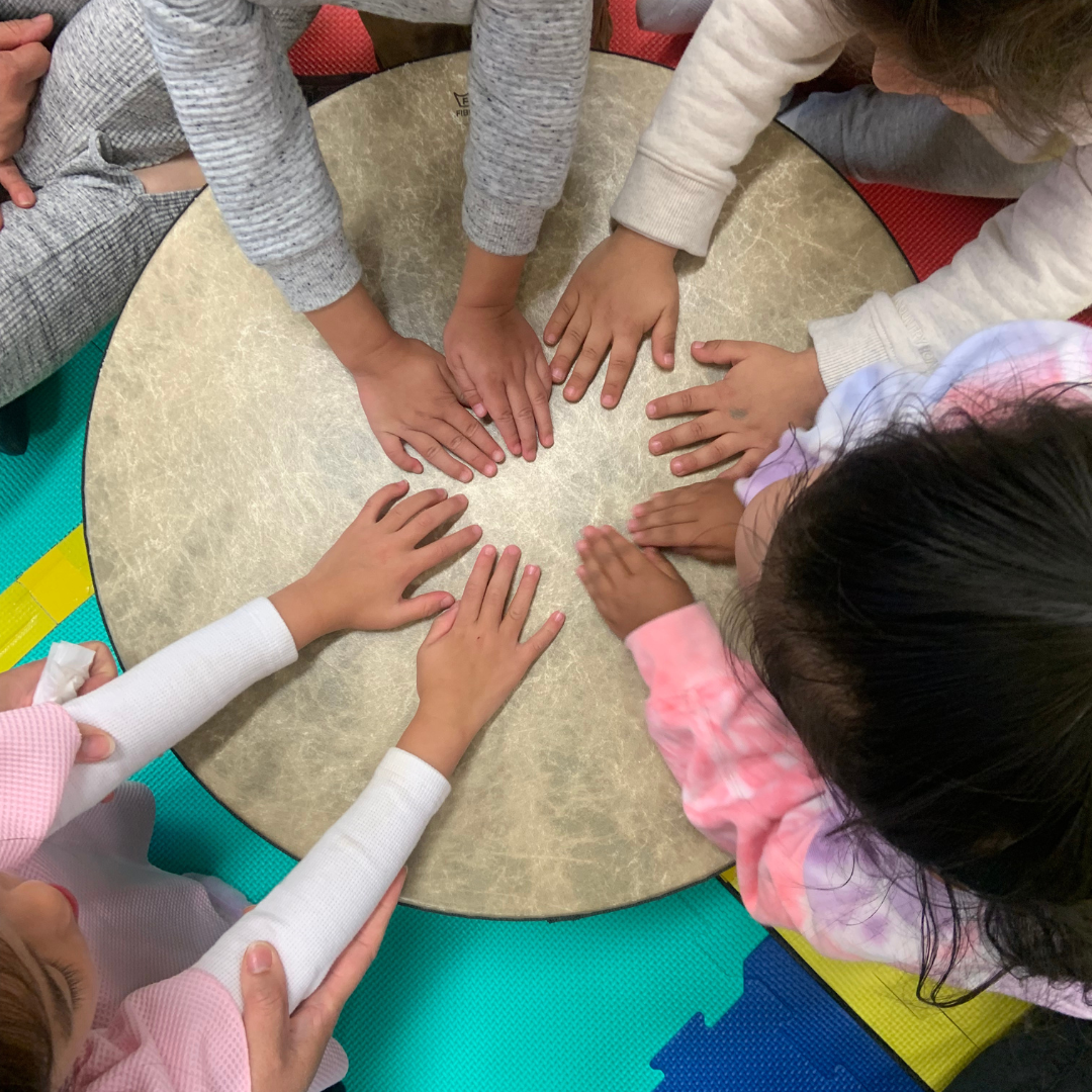 Preschoolers playing on a big remo drum